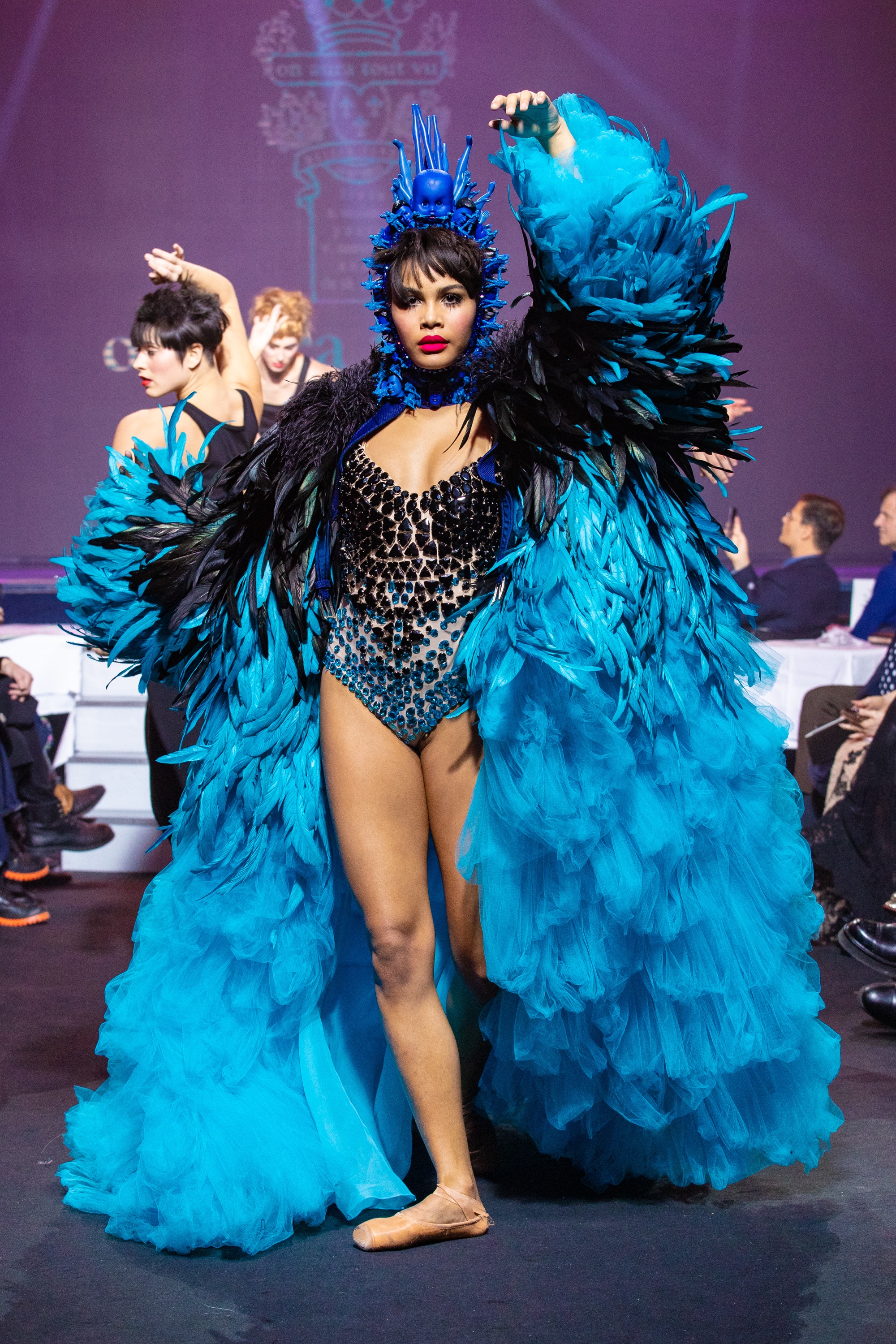 a model wearing  bleu feathers and tull   coat and crystal body and belt  by on aura tout vu haute couture spring summer 2020