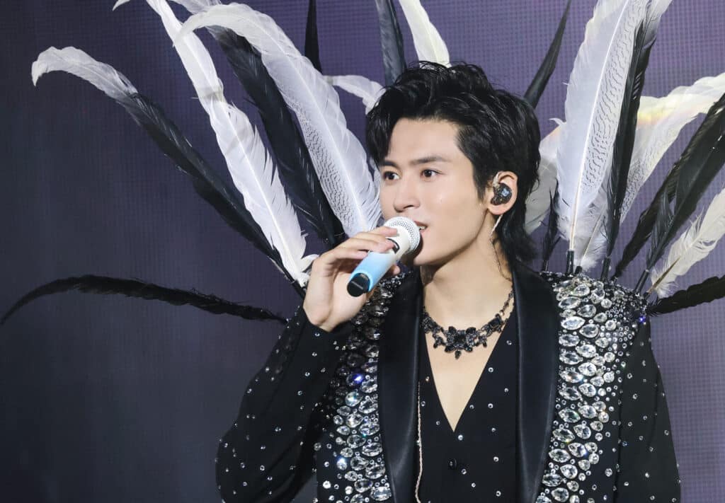 le chanteur Zhang Zhehan en veste sur mesure noire en plumes et cristaux et bijoux par On Aura Tout Vu